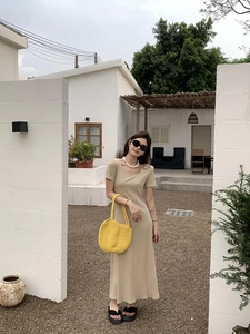 Outdoor shot showing details of a large yellow hand-woven straw shoulder beach bag