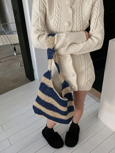 Detail of hand-woven striped straw tote bag in navy and beige stripes on shoulder