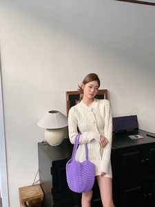 Detail of a bright purple hand-knitted crochet shoulder bag on a white knit cardigan