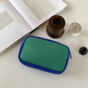 Large capacity green mesh makeup bag with blue trim and zipper in a lifestyle flat lay