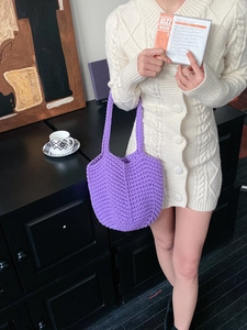 Detail of hand-woven purple crochet bag with thick texture on shoulder of model