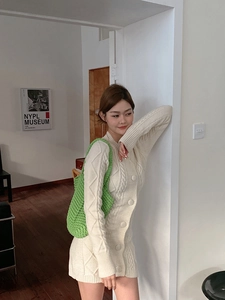 Detail of green hand-woven crochet shoulder bag paired with white cable-knit cardigan