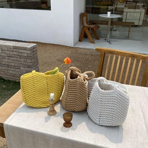 Macro detail of hand-woven tote bags showing V-shaped textures in yellow, brown, and cream