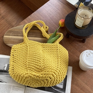Detail of a bright yellow hand-woven cotton shoulder bag on a rustic wooden table