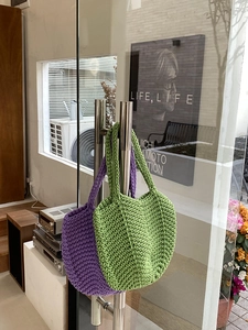 Detail of hand-woven crochet tote bags in green and purple colors with textured fabric