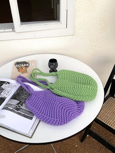 Detail of handmade woven hollow tote bags in purple and green on a minimalist table