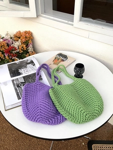Detail of hand-woven cotton rope tote bags in purple and green on a sunny table