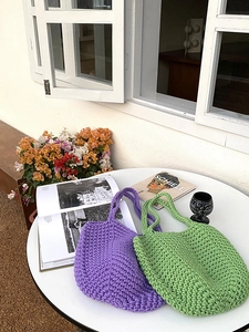 Detail of hand-woven purple and green crochet shoulder bags in an outdoor garden setting