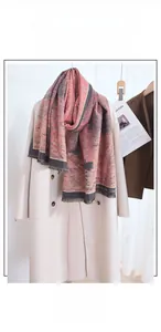Détail d'une écharpe jacquard rose et grise avec de fines franges sur un manteau