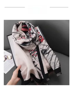Close-up of winter scarf with red floral plum prints and black tassel fringe edges