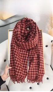 Detail of red and black plaid cashmere-like scarf showing fringe and thick knit texture