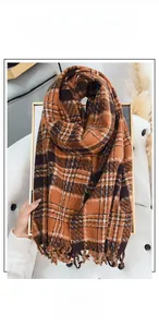 Detail of plaid cashmere-like scarf showing orange and brown weave with soft fringe edges