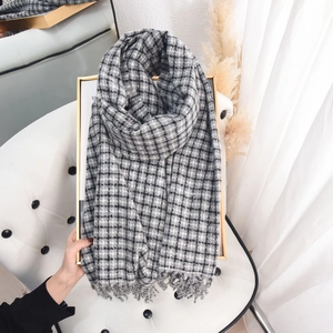 Classic grey checkered cashmere-feel scarf with fringe hanging on a gold frame