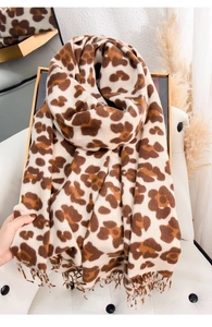 Detail shot of leopard print scarf with tassel trim on a white leather chair