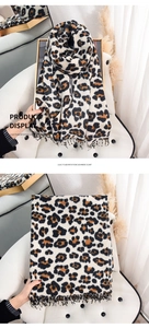 Detail of leopard print imitation cashmere scarf with tassels on cozy armchair