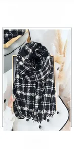 Close-up detail of soft black and white plaid scarf with decorative fringe tassels