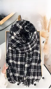 Macro detail of black and beige checkered scarf with soft fringe on a gold display tray