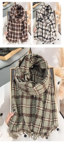 Close-up of winter plaid scarves with fringes in dark brown, beige, and sage green