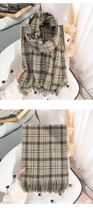 Detail of soft retro plaid scarf with tassel edges in grey-green and brown knit fabric