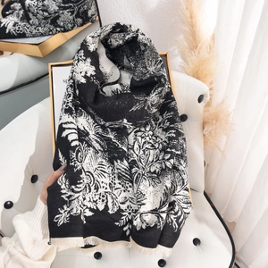 Elegant floral cashmere-feel scarf with fringes on white leather chair