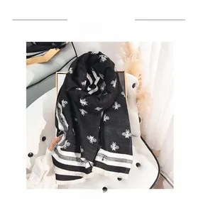 Détail des motifs jacquard d'abeilles et des franges douces sur l'écharpe en cachemire