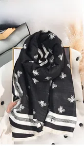 Gros plan d'une écharpe noir et blanc avec motifs abeilles tissés et franges délicates