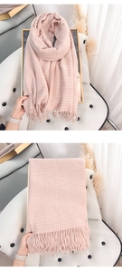 Detail of pink and white plaid scarf featuring soft knit texture and fringe tassels