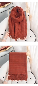 Detail of rust red houndstooth cashmere-like scarf with soft fringe and thick knit texture