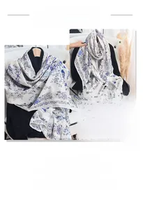 Detail shot of white linen-feel scarf featuring blue floral prints and bird patterns