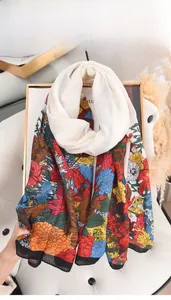 Detailed view of colorful floral print silk scarf displayed on a chic white leather chair