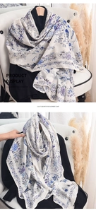 Detailed texture of imitation cashmere scarf featuring floral and bird prints on cream fabric