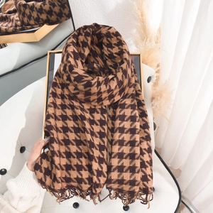 Classic brown houndstooth knitted scarf with fringe, folded on a vintage frame background