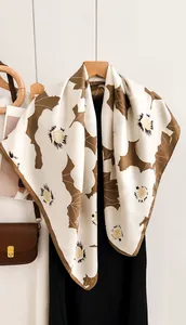 Gros plan d'un foulard en soie à imprimé floral beige et marron aux motifs de feuilles