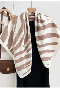 Detailed view of the silk scarf with brown zebra wave patterns hanging on a wooden hanger