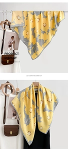 Détail d'une écharpe fleurie jaune en imitation cachemire sur un cintre avec magazine