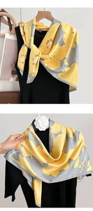 Vue détaillée du foulard en soie à motif floral jaune et gris sur une robe noire