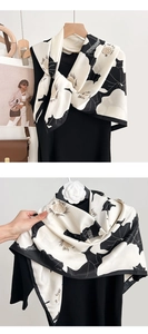 Vue détaillée d'un foulard en soie noir et blanc avec motif floral et éclat satiné