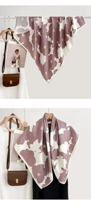 Détail d'un foulard carré à imprimé floral drapé élégamment sur un cintre en bois vintage