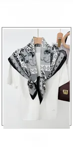 Detail of grey paisley pattern square scarf hanging on a wooden hanger over white t-shirt