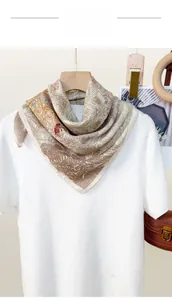 Detailaufnahme eines Seidentuchs mit Blumenmuster an einem weißen T-Shirt und Holzring