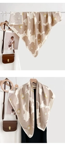 Détail d'un foulard carré à imprimé floral dans des tons terreux sur un anneau en bois