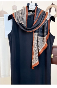 Detail of elegant tricolor silk scarf with paisley and geometric prints on black dress