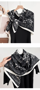 Close-up of vintage floral print silk scarf with contrast white border on a wooden hanger