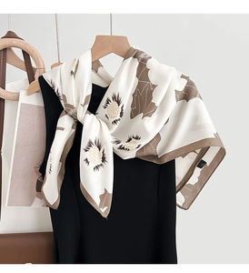 Détail d'un foulard en soie à imprimé floral marron drapé sur une robe noire élégante