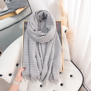 Gray plaid cashmere feel scarf with fringe tassels displayed on a white chair