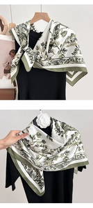 Detail of floral printed scarf with green border showing premium silk-like texture