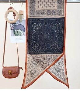Detailed view of bohemian style long scarf with geometric floral print and leather bag