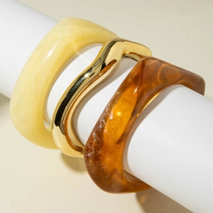 Three-piece set with marble resin and wavy gold metal bangles on a white display
