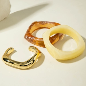 Detailed view of translucent amber and cream resin bangles with gold wavy metal cuff