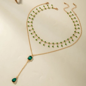 Collana a due strati in oro con pietre color smeraldo e frange di diamanti scintillanti